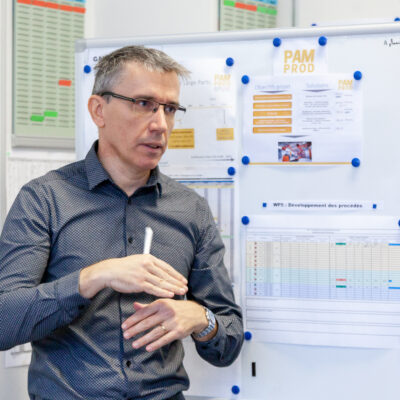 Responsable de production présentant le suivi de projets devant un tableau d'affichage